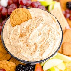 a bowl filled with cream cheese surrounded by fruit and crackers