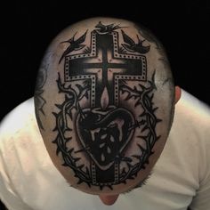 a man with a tattoo on his head has a cross and heart in the middle