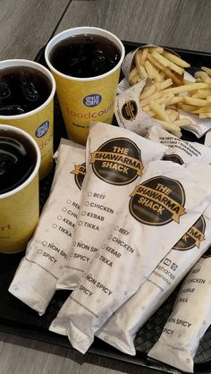 the tray is full of different types of fries and sodas, along with two cups of coffee