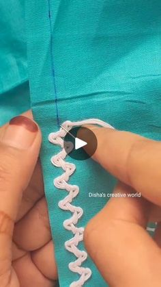 someone is stitching on the side of a green dress with white thread and scissors