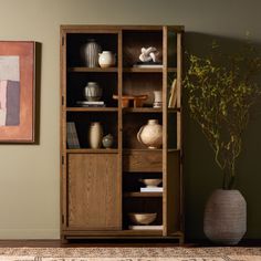 a wooden bookcase sitting next to a vase on top of a rug in a living room