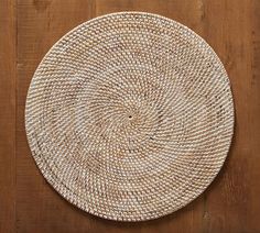 a round woven placemat sitting on top of a wooden table