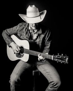 a man with a cowboy hat is playing the guitar