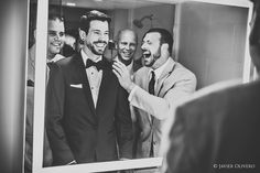 a group of men standing around each other in front of a mirror with their mouths open