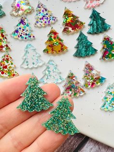 someone is holding out their christmas tree brooches to show off on the table