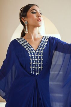 Electric blue kaftan with hand embroidered neckline with zari, mirror, glass beads and white beads.
Components:1
Pattern:Hand Embroidered
Type of Work:Floral Motifs
Neckline:V-Neck
Sleeve Type:Flared Sleeves
Fabric:Chiffon, Lining: Satin
Color:Blue
Other Details:
Front drapes
Note: The hair accessory worn by the model is not for sale
Occasion:Mehendi and Haldi - Aza Fashions Festive V-neck Kurta For Party, Traditional Mirror Work Kaftan For Party, Traditional Party Kaftan With Mirror Work, Bollywood Style V-neck Party Kaftan, Elegant V-neck Dress For Navratri, Party Georgette Kaftan In Maxi Length, Party Georgette Maxi Kaftan, Festive Kaftan With Mirror Work For Reception, Party Kaftan With Mirror Work For Festivals