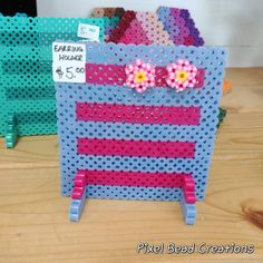 a blue and pink pegboard with flowers on it sitting on a table next to other crafting supplies