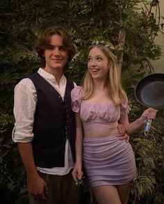 a young man and woman dressed up in costume posing for a photo while holding a frying pan