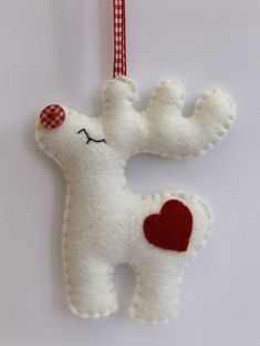 a white stuffed animal with a red heart hanging from it's side on a string