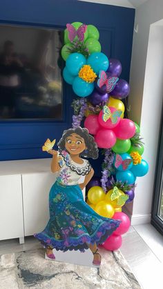 a woman in a blue dress standing next to a bunch of balloons and streamers