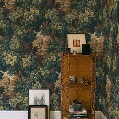 a room with wall paper and pictures on the shelf next to it, along with a chair