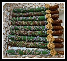 chocolate covered pretzels are lined up in a decorative tray with gold and green icing