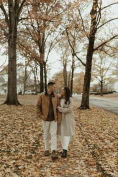 a man and woman standing in the leaves