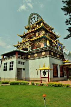 a tall building with a clock on the top of it's roof in front of a green field