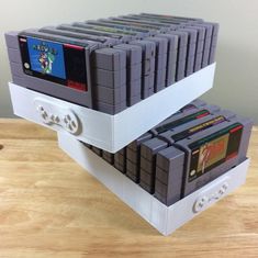 two stacks of video games sitting on top of a wooden table next to each other