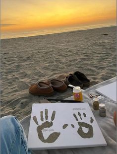 someone is painting their hand and foot prints in the sand at sunset on the beach