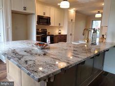 a large kitchen with marble counter tops and stainless steel appliances in the middle of it