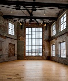 an empty room with large windows and wooden floors