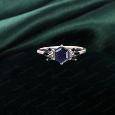 an engagement ring with a blue stone in the center on a green velvet background,