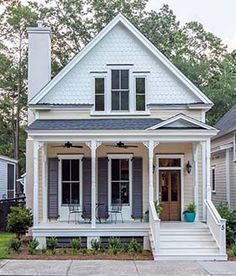 a white house with gray shutters and two story porches on the front door