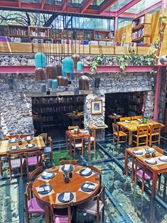 an indoor dining area with tables, chairs and bookshelves on the wall above