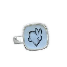 This adorable Rabbit ring will bring you joy every time you wear it. I carved the sterling silver ring setting from a block of wax, then cast that wax ring into metal and molded it so I can make multiples. This ring setting then gets a layer of vitreous enamel (fine glass) and fired at 1400 in a kiln four separate times to build strength and color saturation . Finally I take an illustration from my sketchbook, turn it into an enamel  screen print, and fire that on the top for a durable, waterpro Rabbit Ring, Bunny Jewelry, Rabbit Jewelry, Wax Ring, Vitreous Enamel, Sterling Silver Rings Set, Build Strength, Silver Ring Set, Dog Jewelry