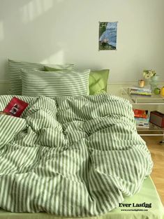 a bed with green and white striped comforter on top of it in a bedroom