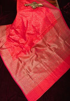 The Authentic Banarasi Dotted Trellis pattern Pure Dupion Silk saree in Coral Pink, embellished with a Kadhuwa Zari Border, is a true embodiment of timeless elegance and traditional craftsmanship. The intricate Dotted Trellis pattern woven into the fabric adds depth and texture, creating a mesmerizing visual appeal that speaks to the artistry of Banarasi weaving. The Coral Pink hue lends a soft and feminine touch to the saree, while the Kadhuwa Zari Border enhances its beauty with its rich golden sheen and intricate detailing. Each thread of zari is meticulously woven by skilled artisans, adding a touch of opulence and grandeur to the ensemble. Crafted from pure Dupion Silk, this saree drapes gracefully and exudes a luxurious feel. Whether worn for weddings, festive occasions, or cultural Saree Drapes, Dupion Silk Saree, Cultural Celebration, Dupion Silk, Trellis Pattern, Banarasi Sarees, Blouse Fabric, Coral Pink, Exquisite Design