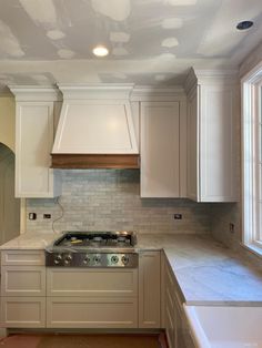 an empty kitchen with white cabinets and marble counter tops