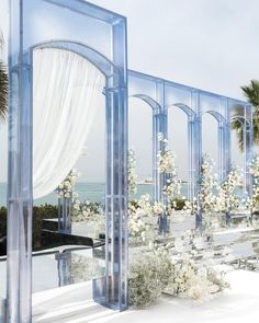 an outdoor wedding setup with white flowers and greenery on the side, surrounded by palm trees