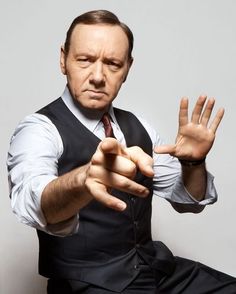 a man in a vest and tie holding his hands out