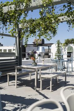 an outdoor dining area with tables and chairs under a pergolated arbor on the roof