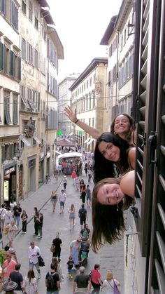 two girls are hanging upside down in an alleyway with many people walking on the sidewalk