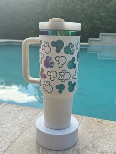 a cup with mickey mouses on it sitting next to a pool