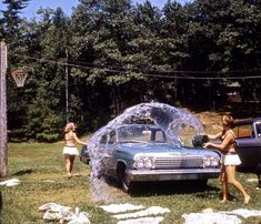 two women washing a car with a sprinkler