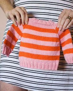 a woman holding an orange and pink sweater