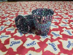 two glitter cups sitting on top of a red and white tablecloth with the word texas printed on it