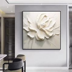 a large white flower is hanging on the wall above a dining room table and chairs