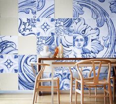 a blue and white tiled wall with two wooden chairs in front of the dining table