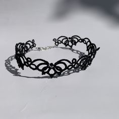 a black lace bracelet on a white surface with shadows from the sun shining through it