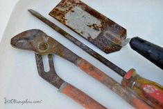 three old tools are laying on the counter top, one is rusty and the other is rusted