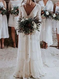 a group of women standing next to each other wearing white dresses and holding bouquets