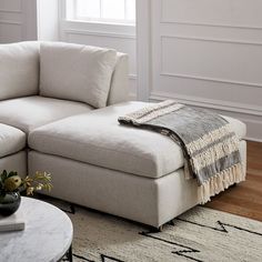 a living room with a sectional couch and coffee table in front of a white wall