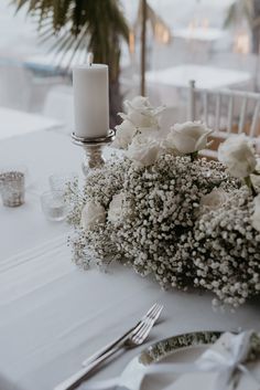 the table is set with white flowers and silverware