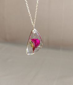 a necklace with a pink flower inside of it