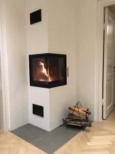 a fire place in the corner of a room with wooden flooring and white walls