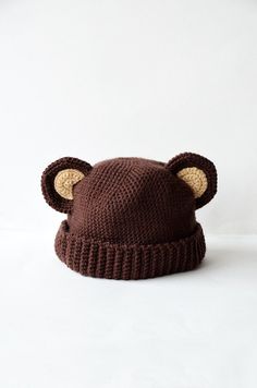 a brown knitted hat with ears is shown on a white surface, it looks like a bear's head