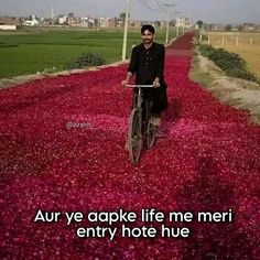 a man riding a bike down a road covered in red flowers with the words, aur ye apke life me meri entry hot hue