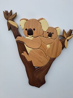 a wooden cutout of two koalas sitting on a tree branch with leaves