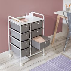 a white and gray cart with drawers on it in a pink room next to a desk